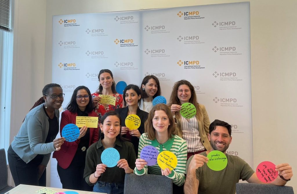 A group of smiling people hold colourful pieces of paper with their ideas on them.