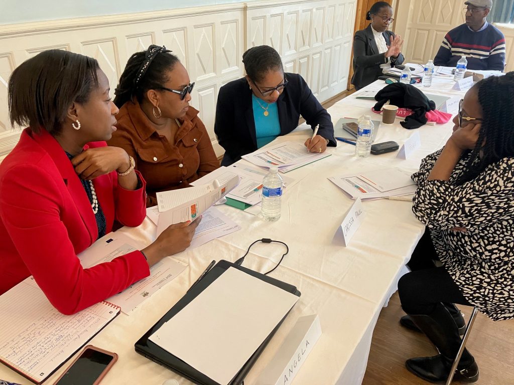 Three women sitting at a table together. One woman is writing notes.