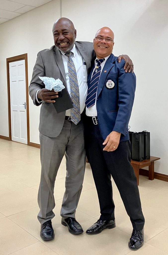 Two men in suits hugging and smiling at the camera.