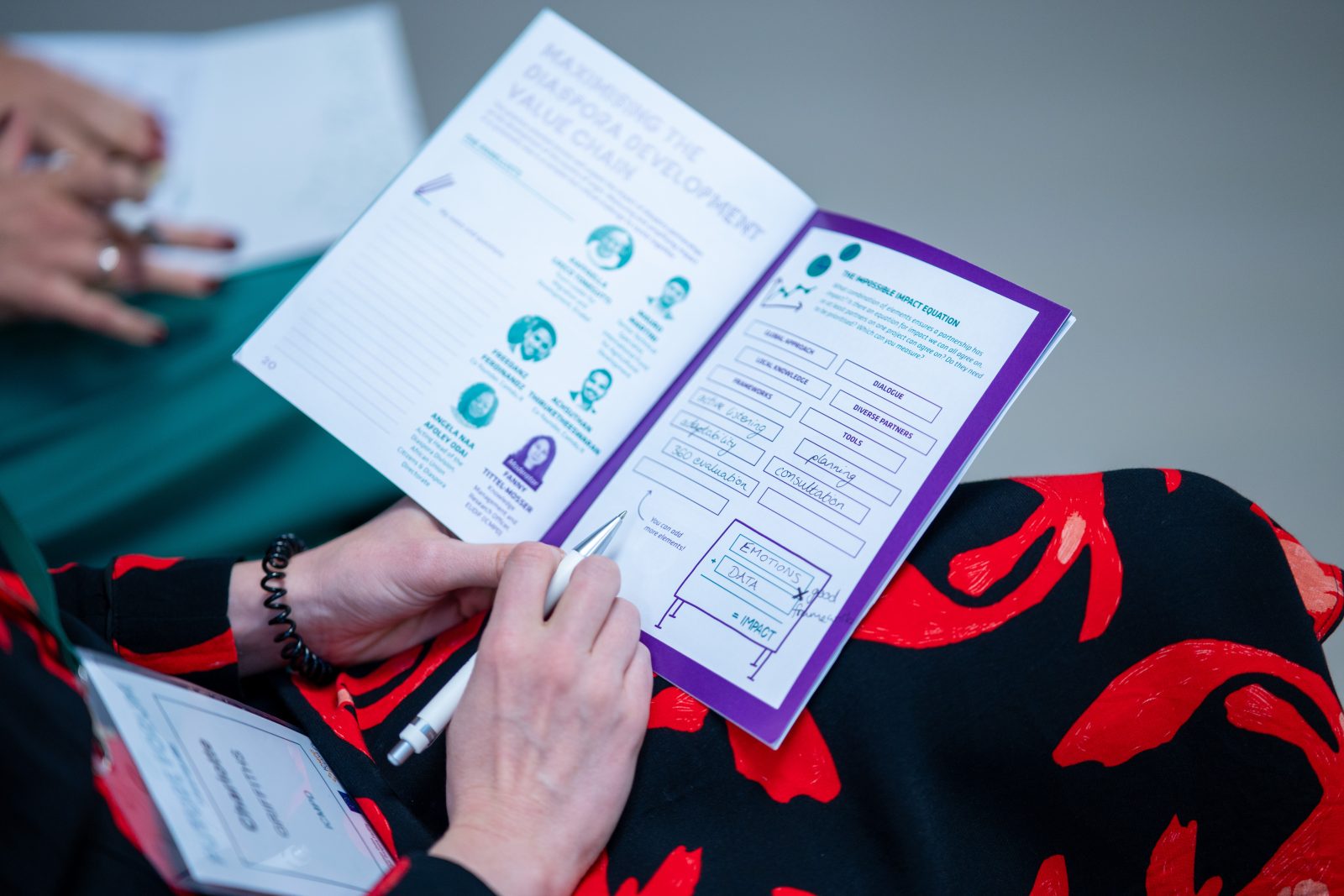 A woman's hands holding a pen and booklet.